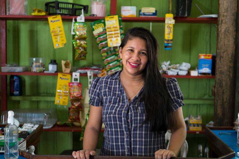 Mulher sorrindo dentro do seu mercado em comunidade no Amazonas.