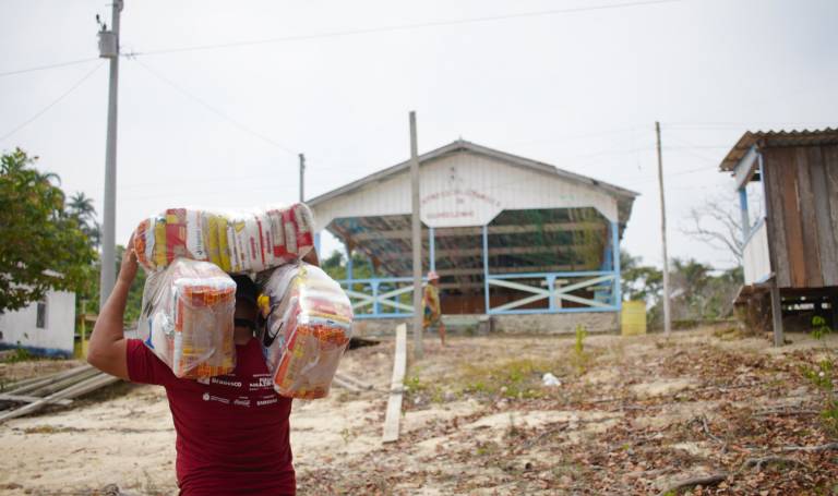 Colaborador da Fundação Amazônia Sustentável (FAS) levando cestas básicas para comunidade indígena localizada no Amazonas.