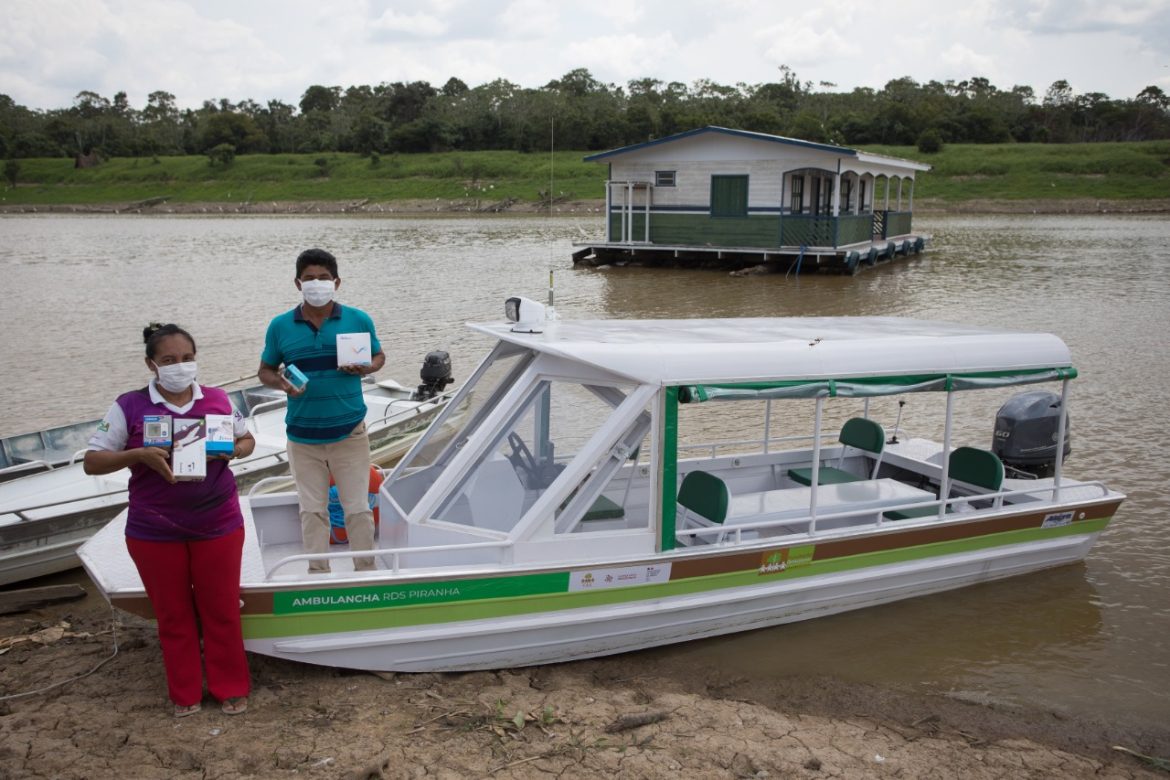 Pessoas recebendo equipamentos de saúde para sua comunidade ribeirinha no Amazonas.