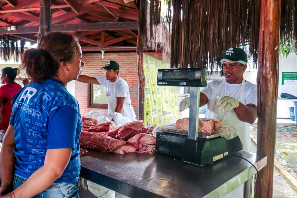 Mulher comprando Pirarucu, peixe típico da Amazônia, durante feira realizada pela Fundação Amazônia Sustentável (FAS).