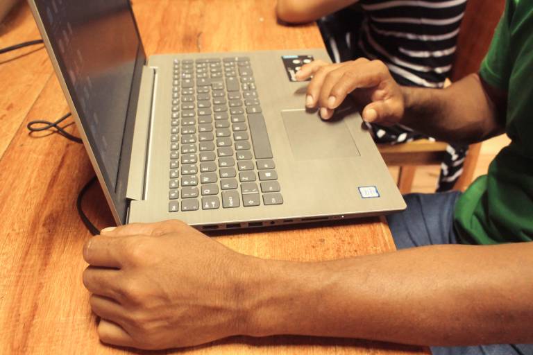 Homem mexendo em notebook durante atividade prática do projeto de conectividade promovido pela Fundação Amazônia Sustentável (FAS).