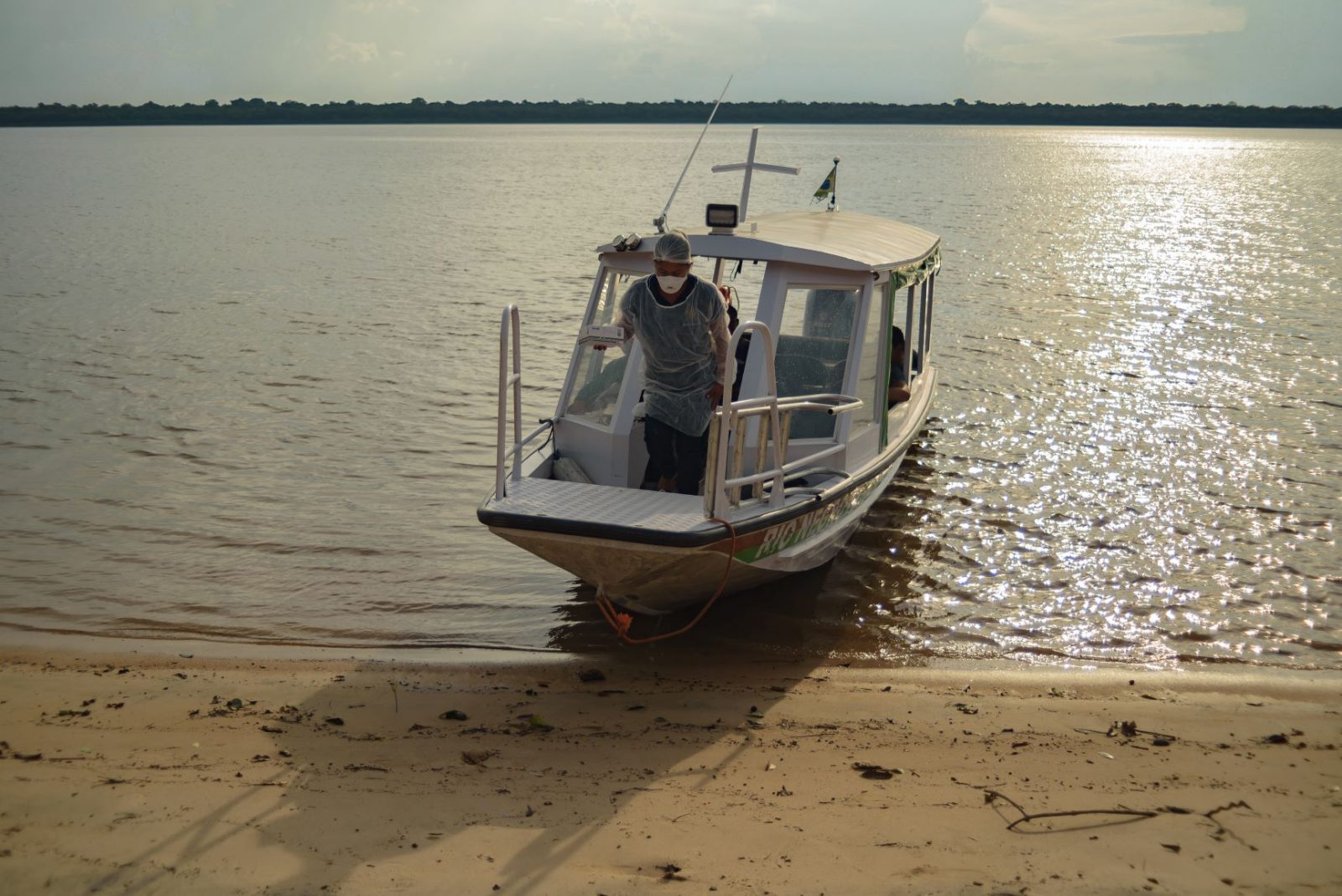 Agente de saúde saindo de lancha segurando equipamentos de saúde.