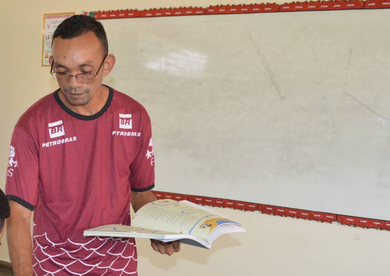 Professor segurando livro e dando aula em escola no interior do Amazonas.