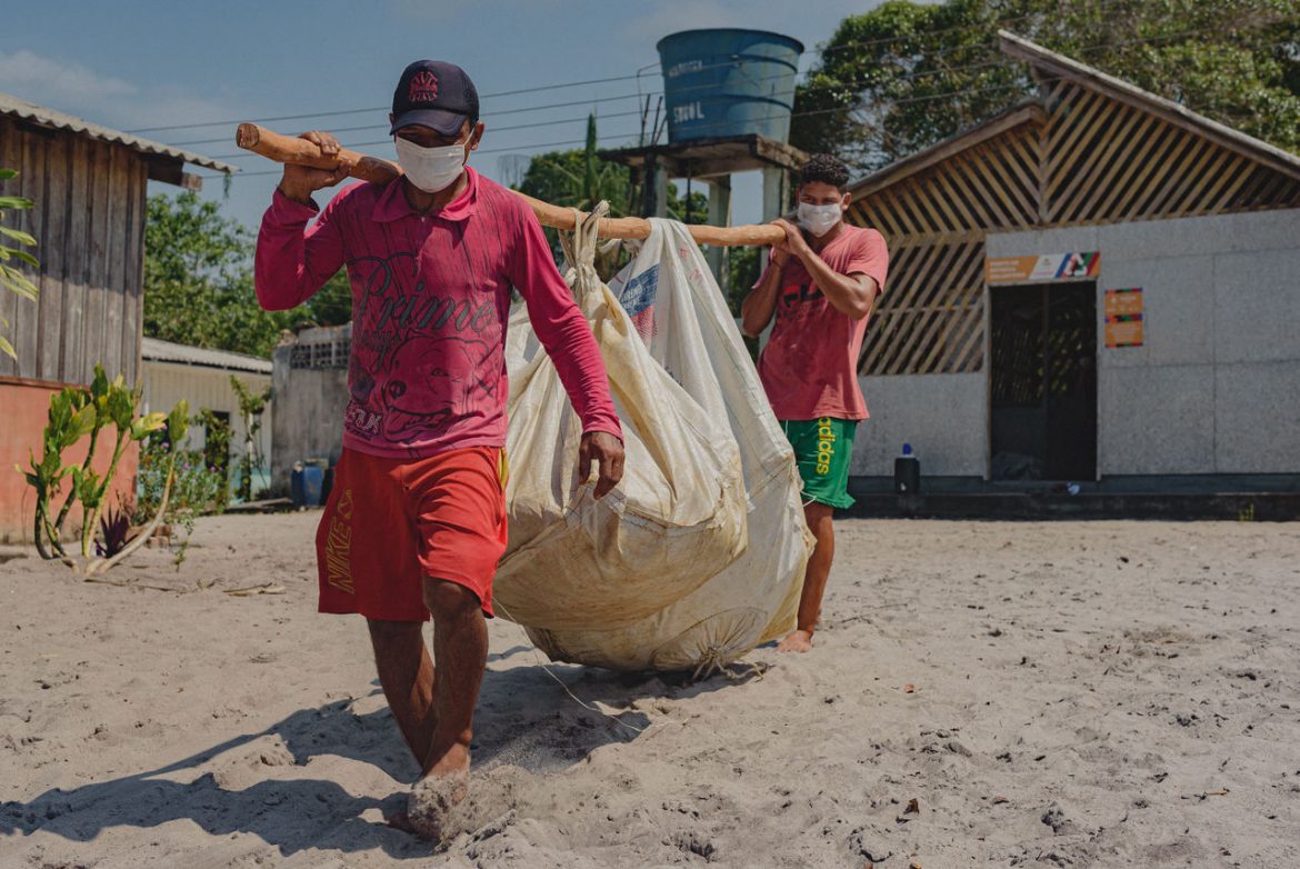 Homens carregando resíduos sólidos que foi coletado em áreas de proteção ambiental no Amazonas.