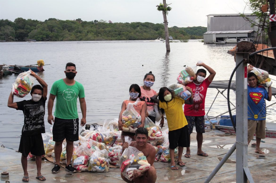 Moradores de comunidades ribeirinhas recebendo doações de cestas básicas.