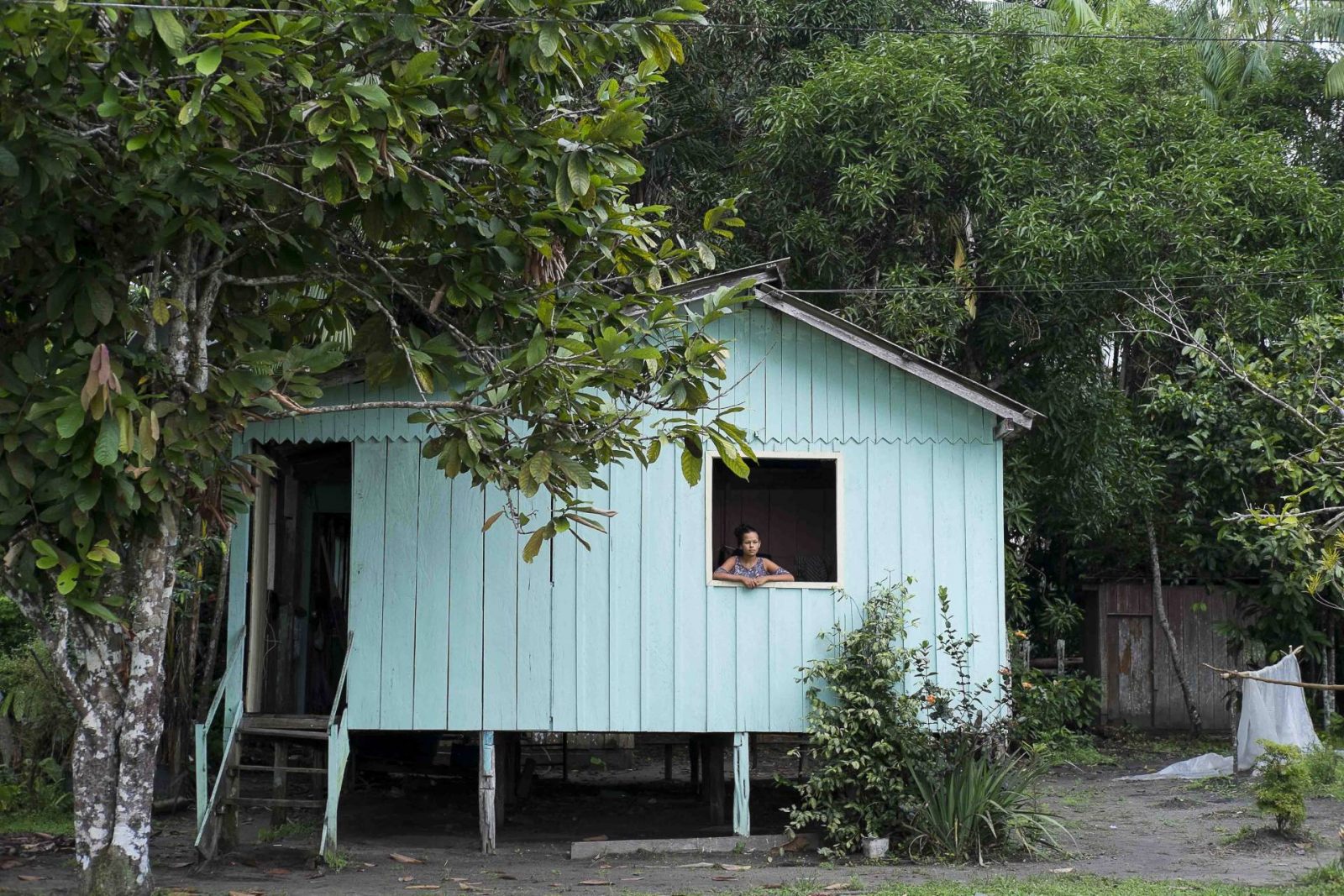 Mulher na janela de sua casa localizada no interior do Amazonas.