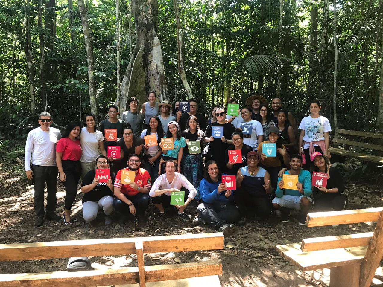 Pessoas reunidas em sala de aula na floresta.