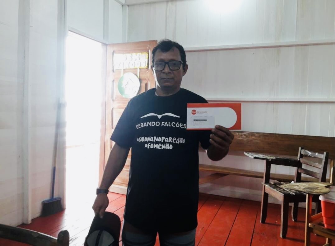 Homem recebendo cartão alimentação através de uma iniciativa entre a Fundação Amazônia Sustentável (FAS) e a Organização Não Governamental (ONG) “Gerando Falcões”.