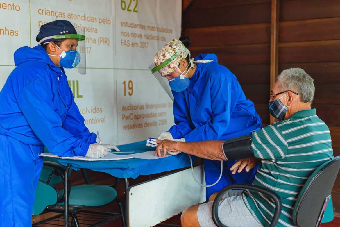 Equipe de saúde aferindo temperatura de homem em sua comunidade no interior do Amazonas.