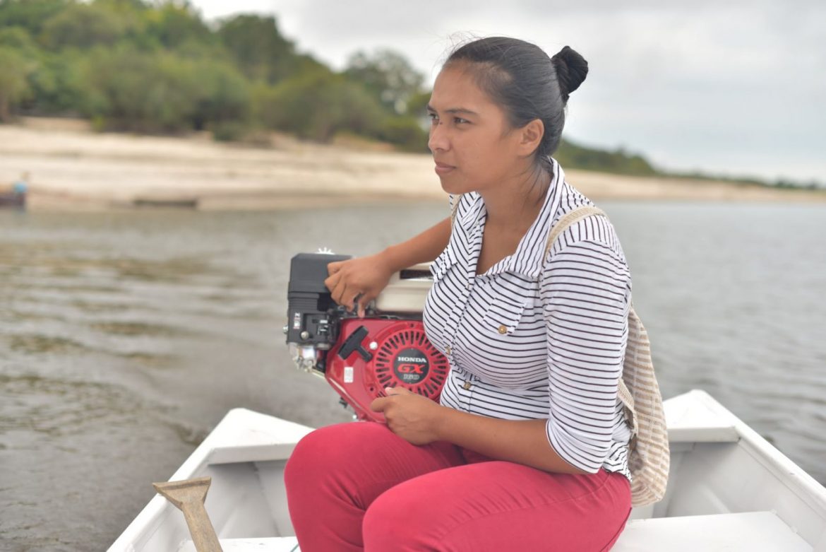 Mulher pilotando barco em rio no Amazonas.
