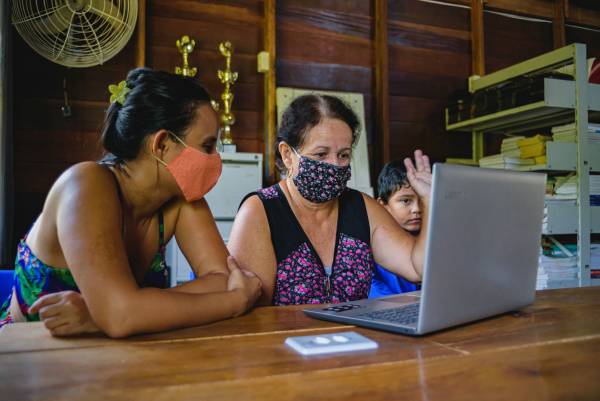 Duas mulheres e uma criança fazendo atendimento de Telessaúde no interior do Amazonas.