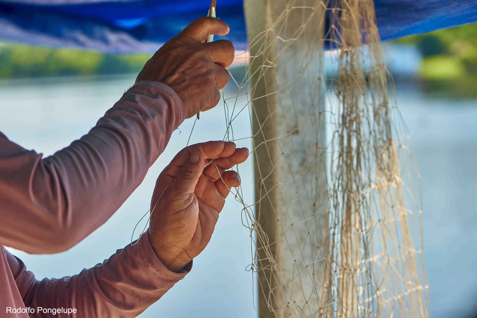 Homem arrumando rede de pesca.