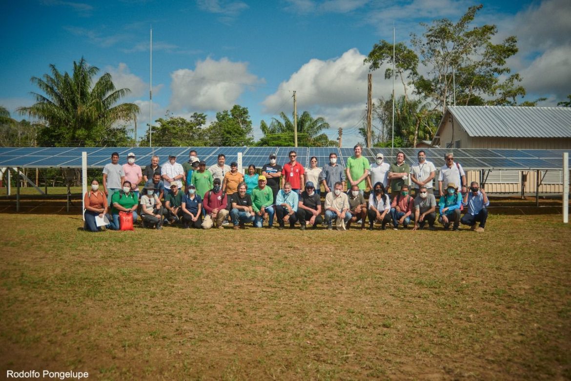 Grupo de pessoas reunidas em frente a painel solar, instalado em comunidade no interior do Amazonas.