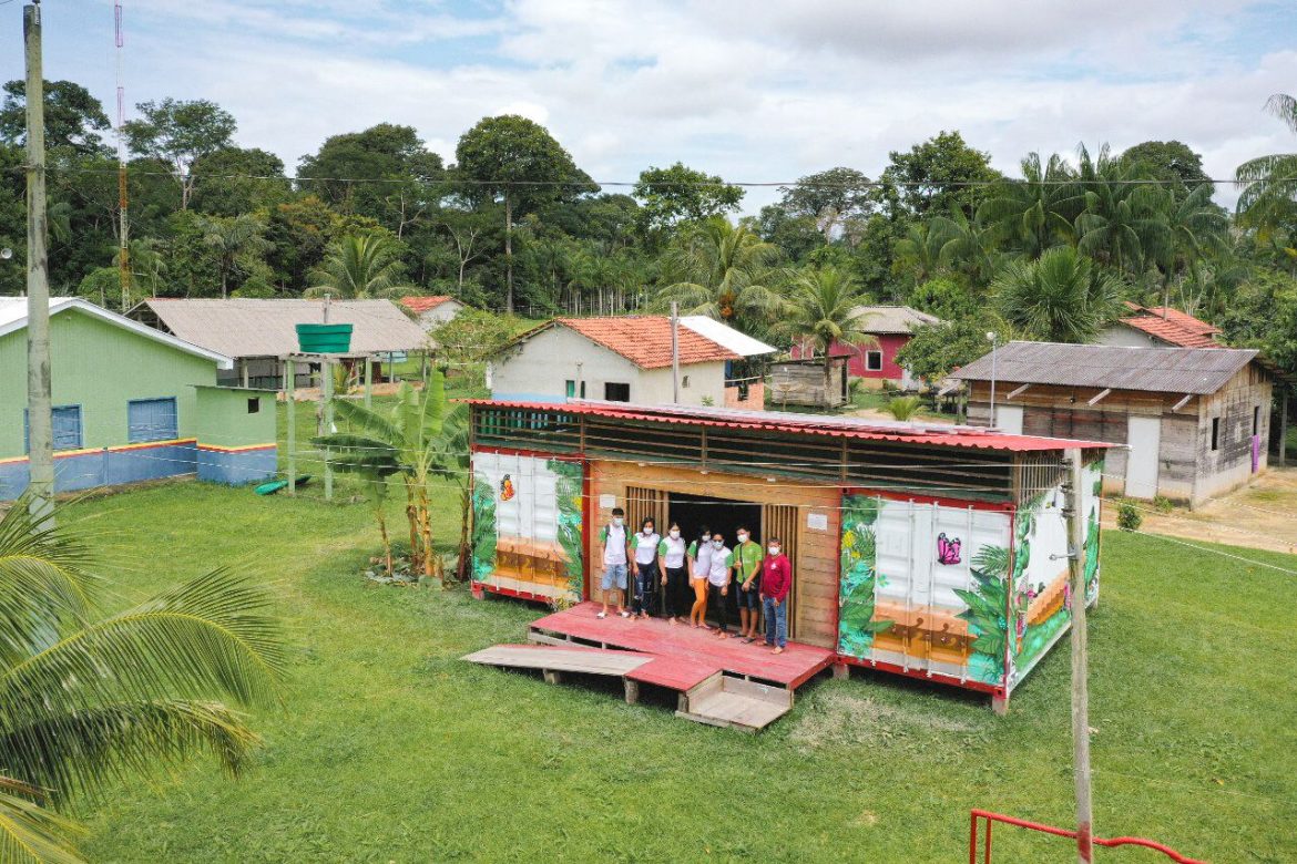 Pessoas reunidas em frente ao Solar Community Hub, realizado pela Dell Technologies, em parceria com a Fundação Amazônia Sustentável (FAS), na comunidade Boa Esperança, localizada na Reserva de Desenvolvimento Sustentável (RDS) do Rio Amapá.