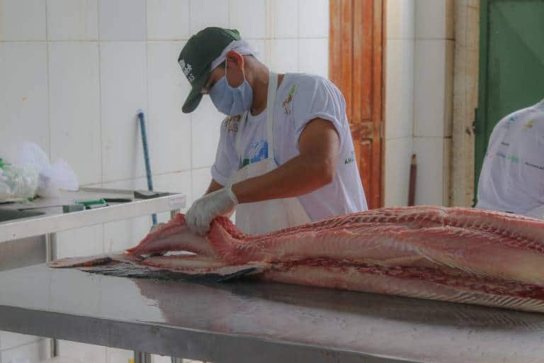 Homem cortando peixe na Feira da FAS, realizada pela Fundação Amazônia Sustentável (FAS) em parceria com a Associação dos Moradores e Usuários da RDS Mamirauá Antônio Martins (Amurman).