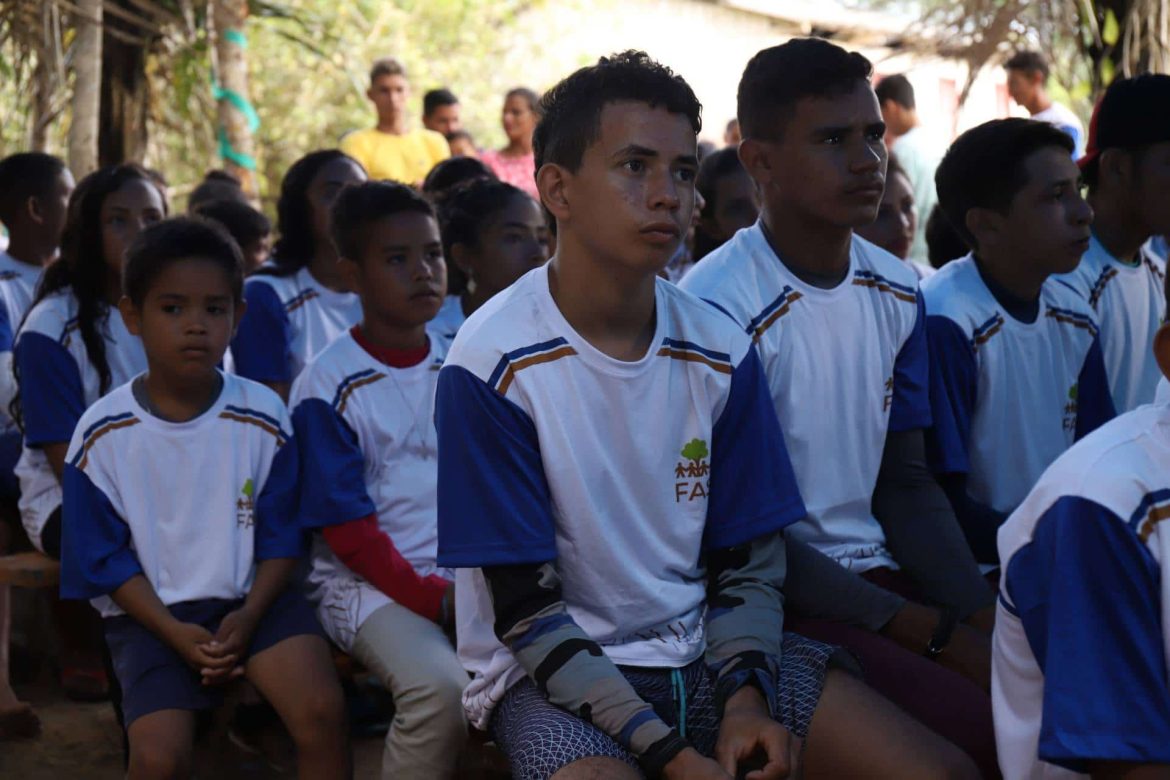 Crianças e jovens sentados participando de atividade realizada pela Fundação Amazônia Sustentável (FAS).