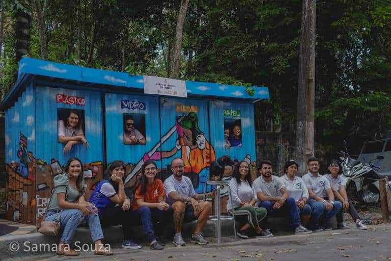 Pessoas sentadas em frente ao Ponto de Entrega Voluntária, instalado na Marina do Davi, terminal fluvial situado na zona Oeste de Manaus.