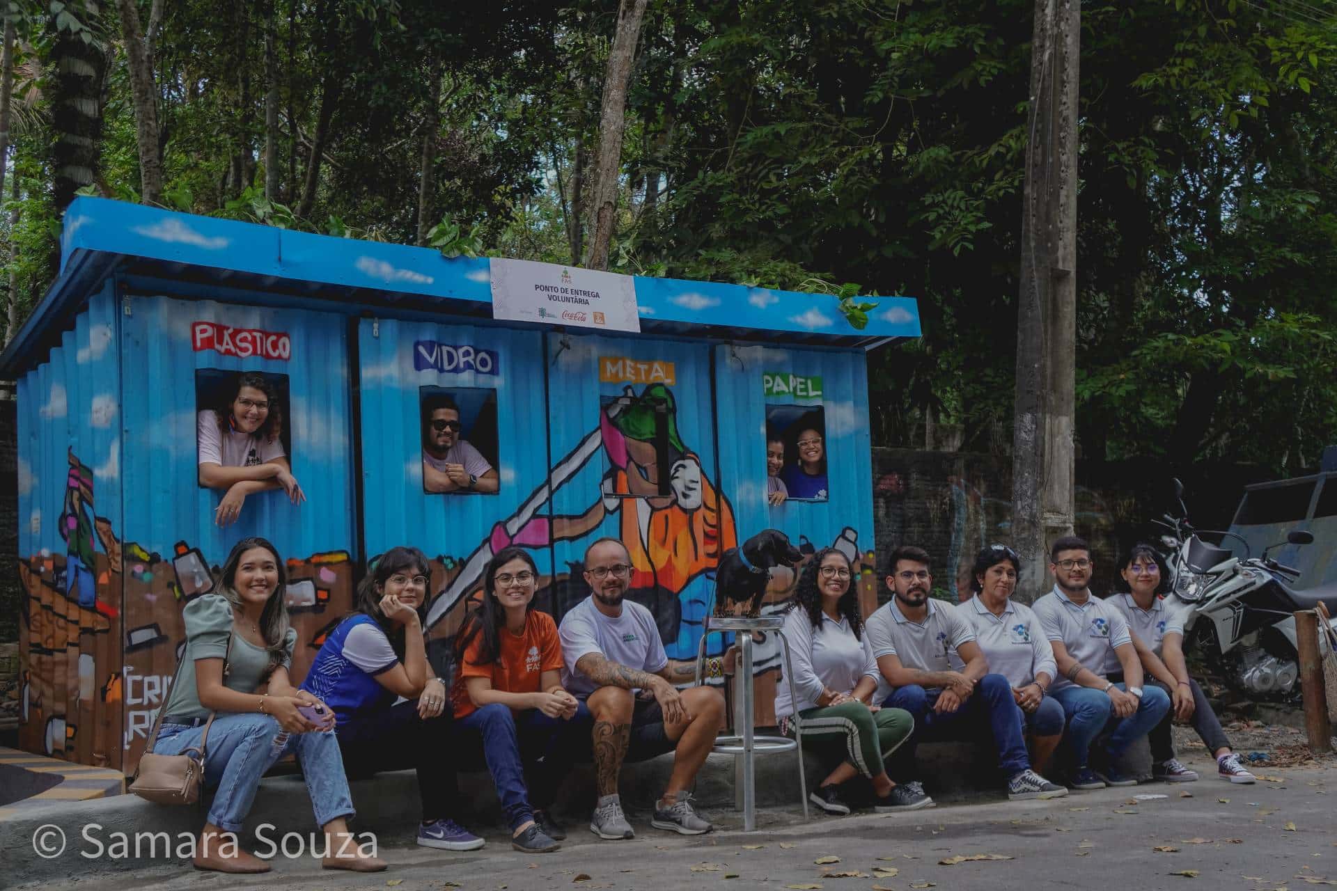 Pessoas sentadas em frente ao Ponto de Entrega Voluntária, instalado na Marina do Davi, terminal fluvial situado na zona Oeste de Manaus.