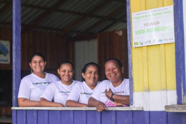 Quatro mulheres empreendedoras sorrindo na janela da Pousada Vista Rio Negro, localizada no Amazonas.