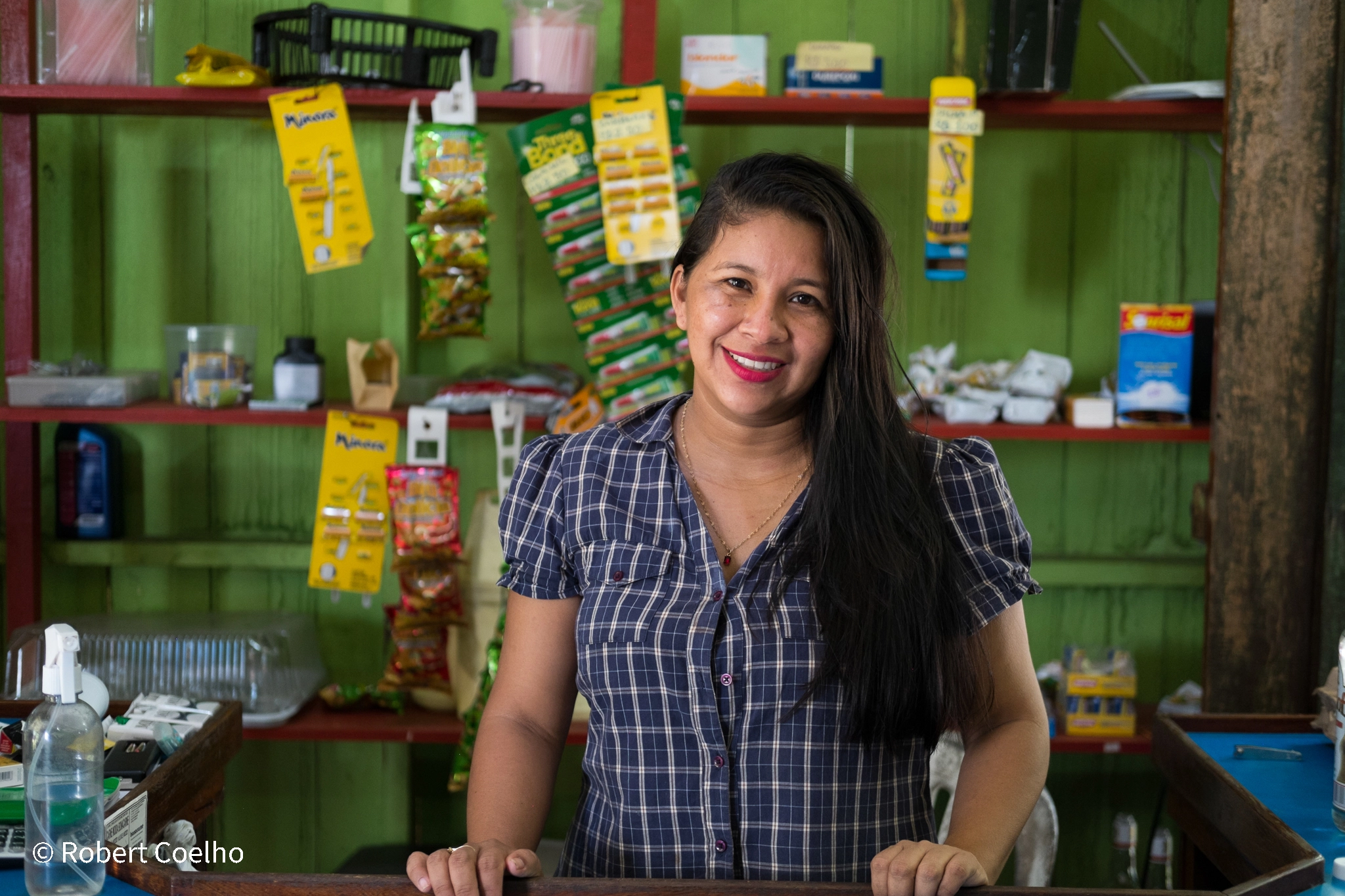 Mulher empreendedora sorrindo dentro do seu estabelecimento, apoiado pela Fundação Amazônia Sustentável (FAS).