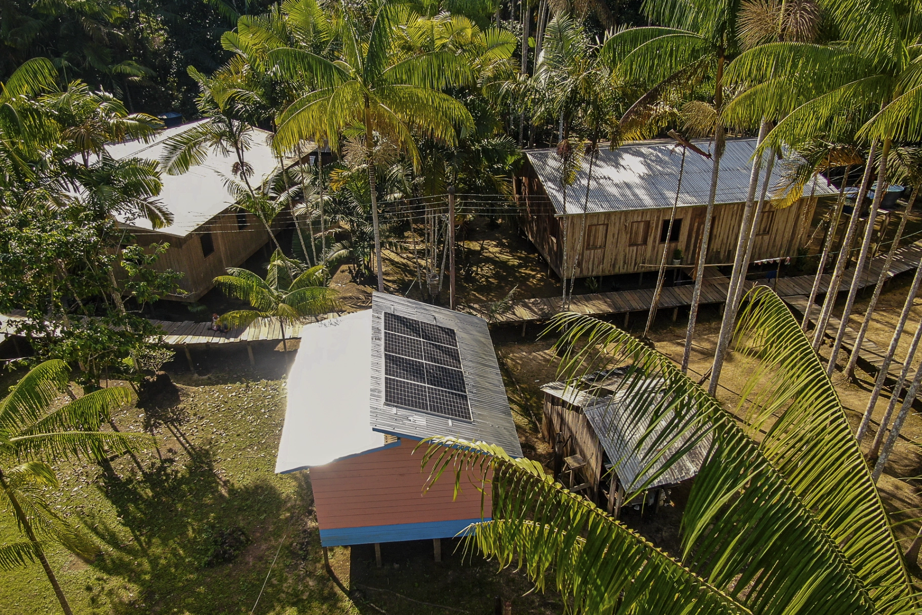 Vista aérea de uma casa com placa solar no meio da floresta amazônica.