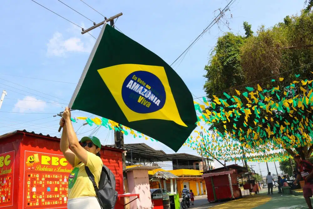 Mulher segurando bandeira escrito "Eu voto na Amazônia Viva", campanha criada pela Fundação Amazônia Sustentável (FAS).