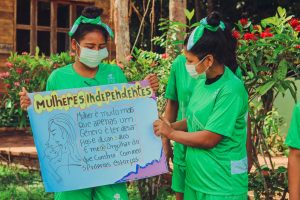 Duas meninas ribeirinhas segurando cartaz em atividade do projeto Deixa a mana Jogar, realizado pela Fundação Amazônia Sustentável (FAS).