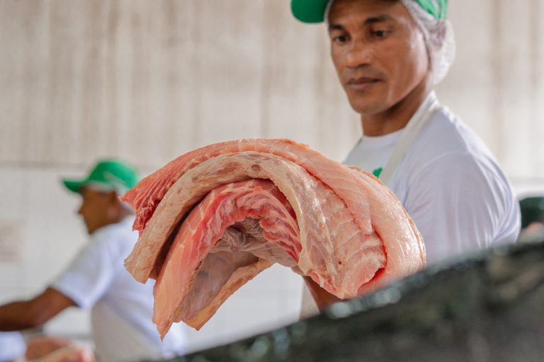 Homem segurando um pedaço de pirarucu, peixe típico da Amazônia.
