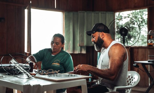Duas pessoas fazendo artesanato na Comunidade do Sacará, localizada na Amazônia.