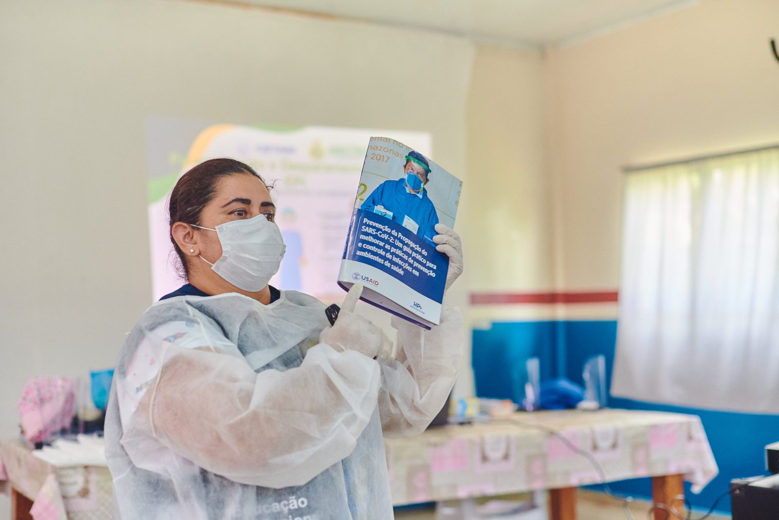 Enfermeira apresentando material de prevenção e proteção ao COVID19, produzido USAID para comunidade no Amazonas.