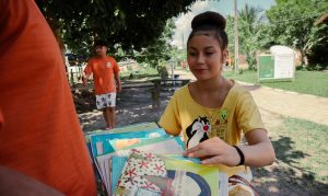 Garota escolhendo livro para fazer atividade de leitura em sua comunidade no interior do Amazonas.