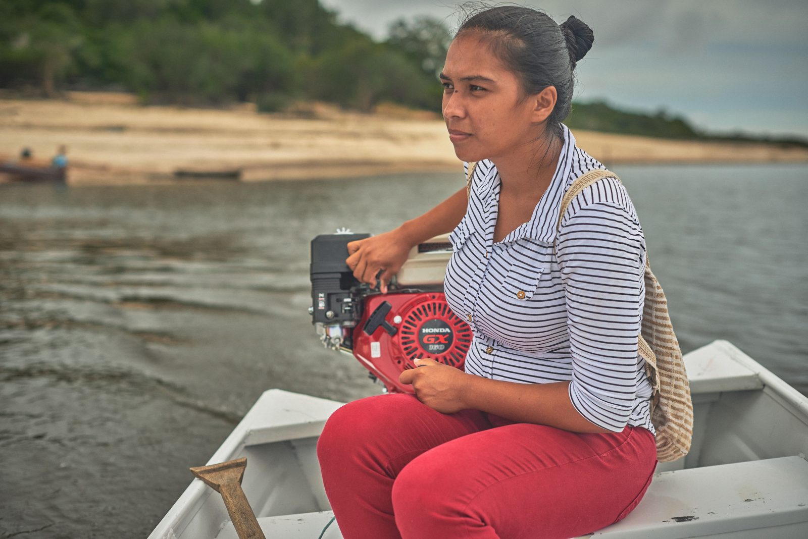 Mulher pilotando lancha para chegar até sua comunidade no interior do Amazonas.