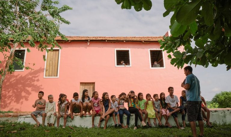 Crianças sentadas prestando atenção em aula realizada pelo colaborador da Fundação Amazônia Sustentável (FAS) durante projeto de educação.