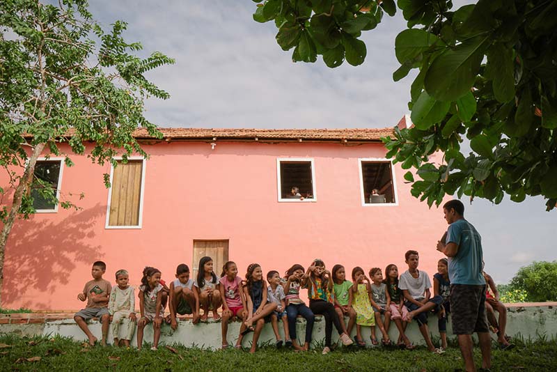 Crianças sentadas prestando atenção em aula realizada pelo colaborador da Fundação Amazônia Sustentável (FAS) durante projeto de educação.