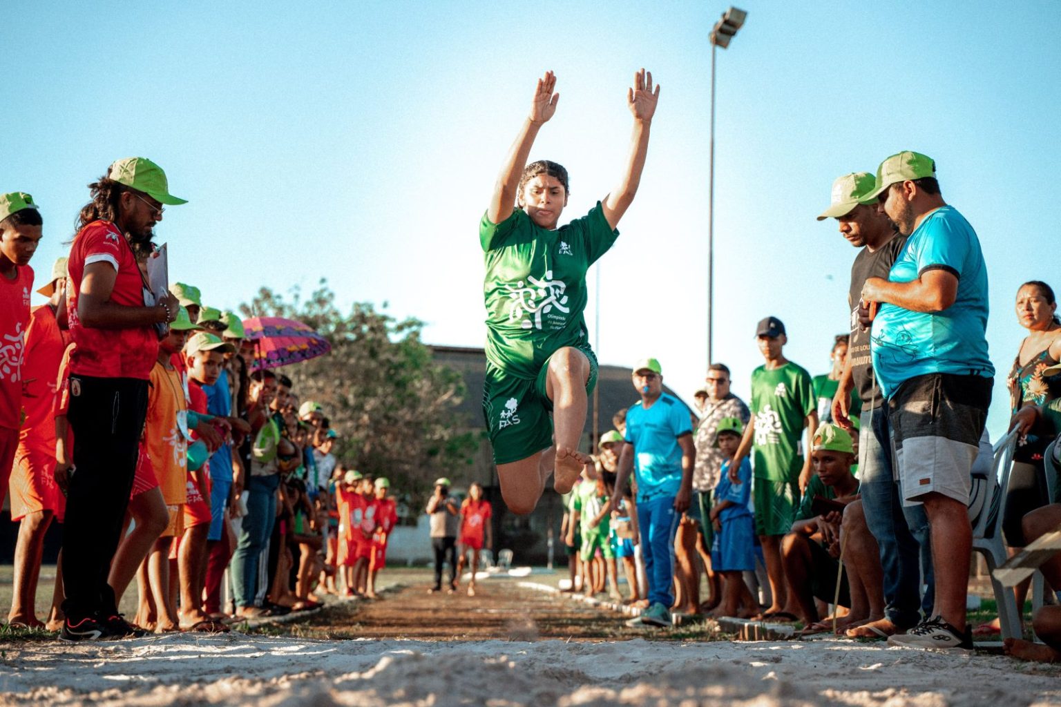 Menina competindo salto à distância durante Olímpiada na Floresta realizada pela Fundação Amazônia Sustentável (FAS).