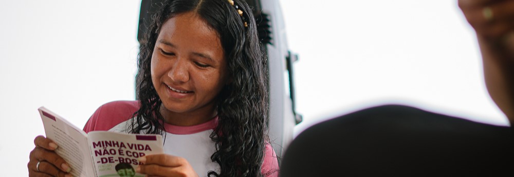 Menina lendo livro através de atividade do Programa de Educação para a Sustentabilidade da Fundação Amazônia Sustentável (FAS).