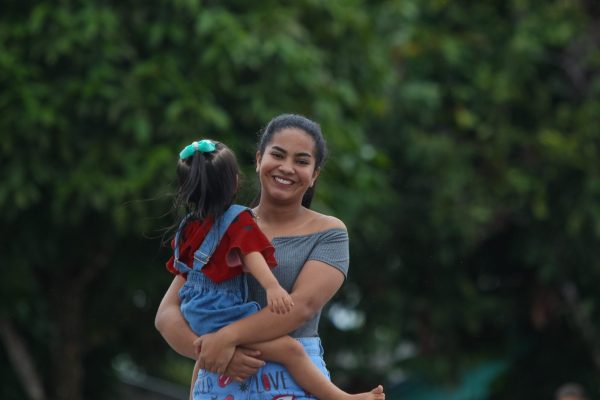 Menina sorrindo e carregando criança, caminhando em comunidade no interior do Amazonas.