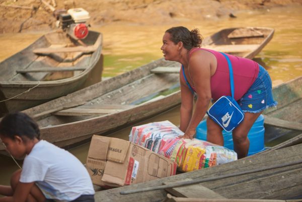 Mulher ribeirinha carregando cesta básica que recebeu através de ação realizada pela Fundação Amazônia Sustentável (FAS) no período de seca no Amazonas.