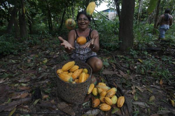 Mulher jogando frutas pra cima e sorrindo.